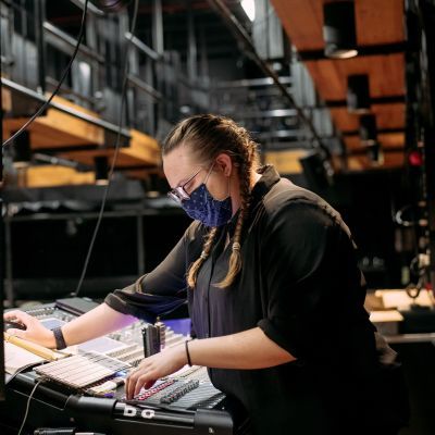 Production Arts student working at a sound desk backstage